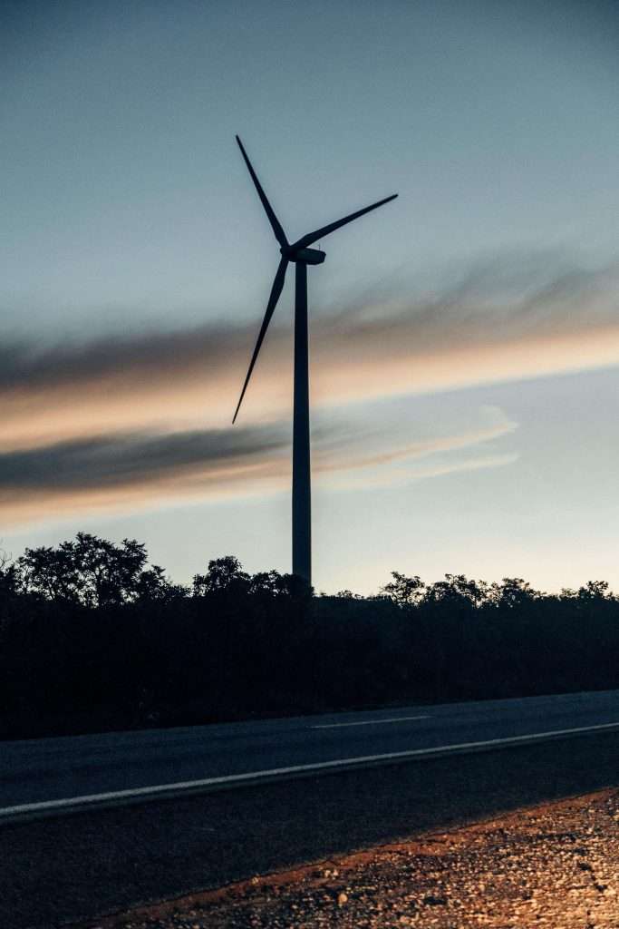 Wind turbine beside road at dusk.